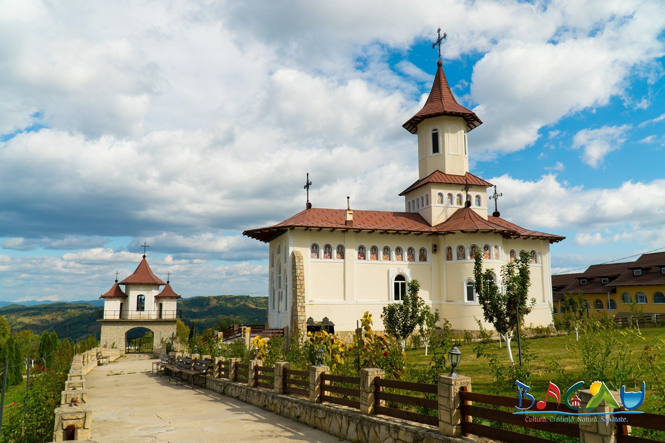 Mănăstirea Ștefan cel Mare de pe muntele Bolovanu, biserică albă cu turlă și acoperiș roșu, sub cer senin